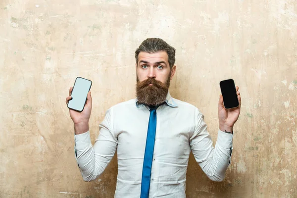 Hipster ou homem barbudo comparar telefone celular e smartphone — Fotografia de Stock