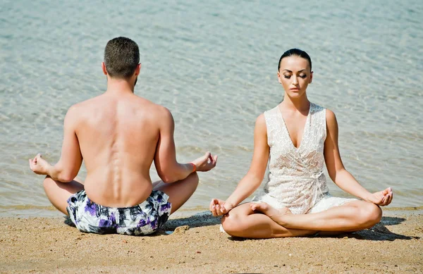Yoga pareja relajante haciendo meditación en la playa —  Fotos de Stock