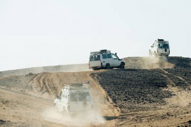 Jeeps bashing through sand dunes in desert clipart