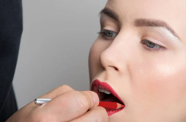 Chica consiguiendo lápiz rojo en los labios a mano de visagiste — Foto de Stock