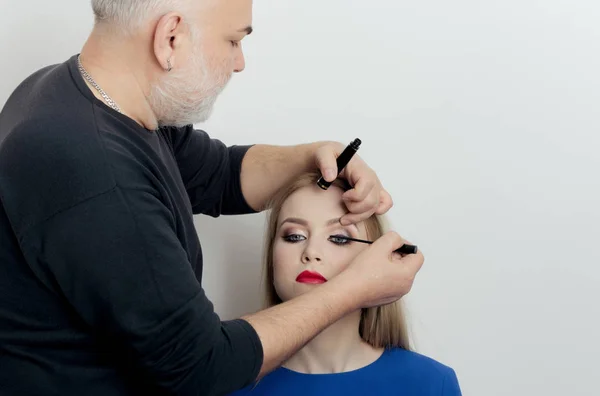 Maquillaje artista aplicar rímel negro en las pestañas de la chica — Foto de Stock