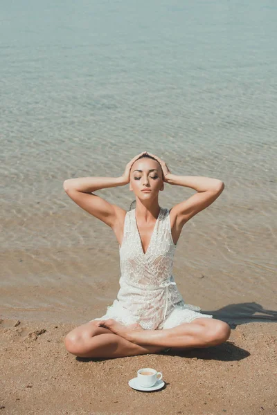 Mujer meditando en pose de yoga con taza de café en el agua —  Fotos de Stock