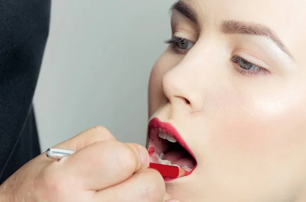 Mulher recebendo lápis vermelho nos lábios à mão — Fotografia de Stock