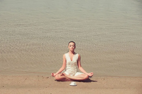 Mujer meditando en pose de yoga con taza de café en el agua —  Fotos de Stock