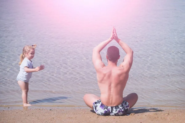 Padre e hijo haciendo ejercicios de yoga en la playa —  Fotos de Stock