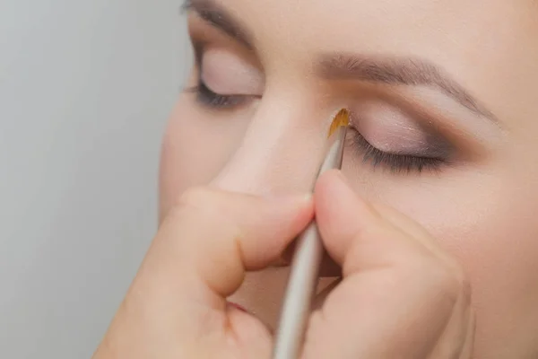 Mão com escova aplicando sombras no rosto da mulher — Fotografia de Stock