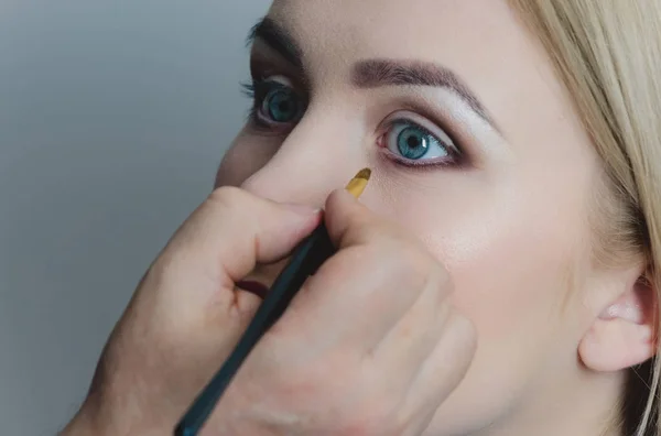Женщина с голубыми глазами получает макияж — стоковое фото