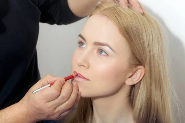Mano de visagiste aplicando lápiz rojo en labios de mujer — Foto de Stock