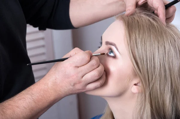 Visagiste aplicar maquillaje de ojos en la cara de chica con cepillo — Foto de Stock
