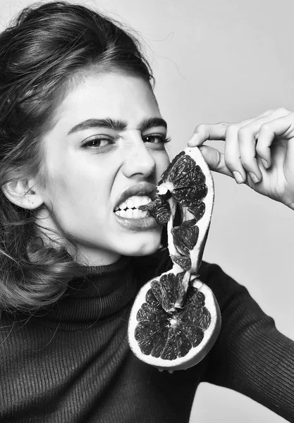 Dívka s grapefruity ovocné řezy má naštvaný obličej — Stock fotografie