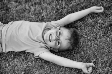 Mutlu bebek çocuk saçlı gözlüklü çimenlerin üzerinde