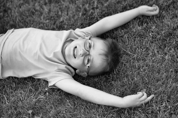 Chłopczyk z włosami w okularach na trawie — Zdjęcie stockowe