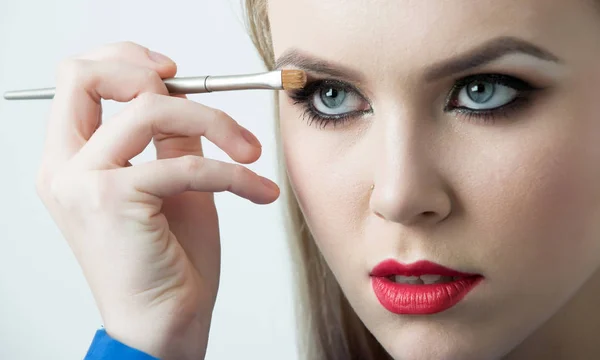 Mujer que aplica sombra de ojos en el ojo con cepillo de maquillaje —  Fotos de Stock