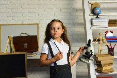 Çocuk deneyler yapar. Kız öğrenci mikroskop ve kalem tutan