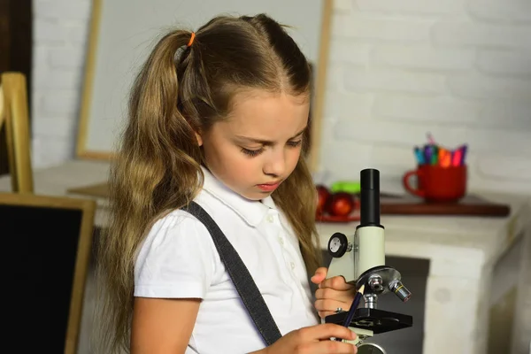 Back to school concept. Schoolgirl holds microscope and pencil — Stock Photo, Image