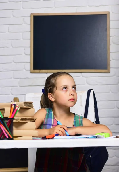 Schoolmeisje met doordachte gezicht tekent in kunstboek — Stockfoto