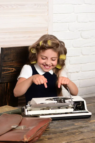 Klein meisje met krultang in haren met typemachine. — Stockfoto