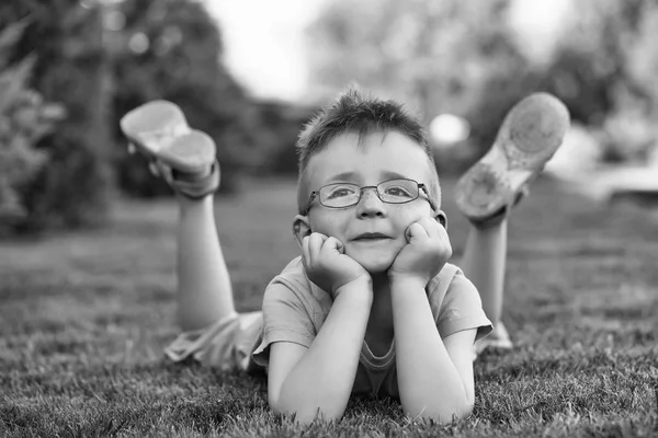 Pojke med hår i glas på gräs — Stockfoto