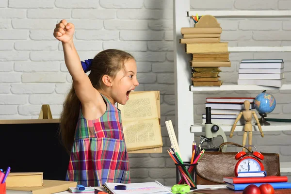 Schoolmeisje met vrolijk gezicht houdt boek en schreeuwt — Stockfoto