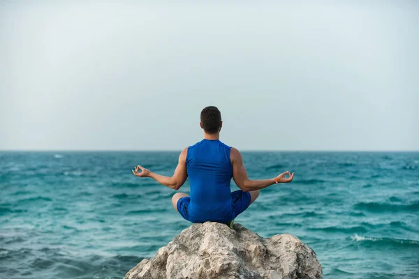 Hombre practicando yoga cerca del océano azul —  Fotos de Stock