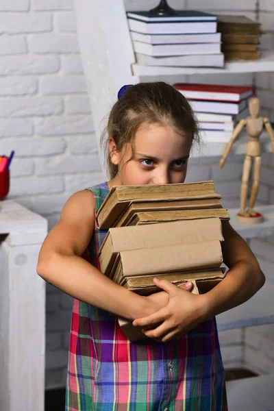 Mädchen in der Nähe eines großen Bücherregals mit Schulbüchern. Schulmädchen mit kniffligen Augen — Stockfoto