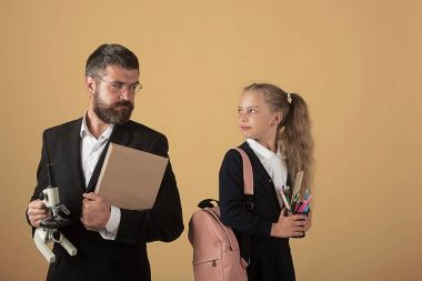 Çocuk ve öğretmen kitap ve mikroskop tutun. Kız çantası ile