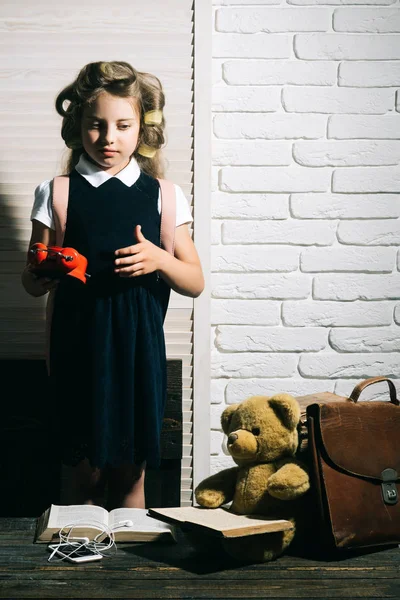 Menina pequena com curler no cabelo com máquina de escrever . — Fotografia de Stock