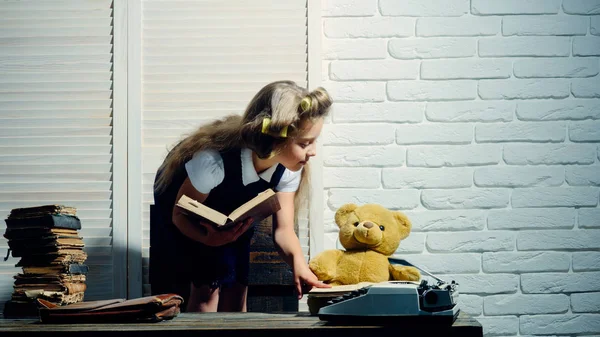 Criança ler livro com pasta e máquina de escrever retro — Fotografia de Stock