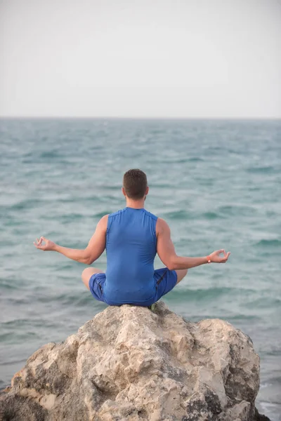 Niño practicando yoga cerca del océano azul —  Fotos de Stock