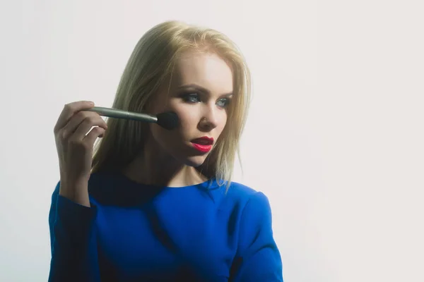 Menina com lábios vermelhos aplicando maquiagem no rosto com escova — Fotografia de Stock