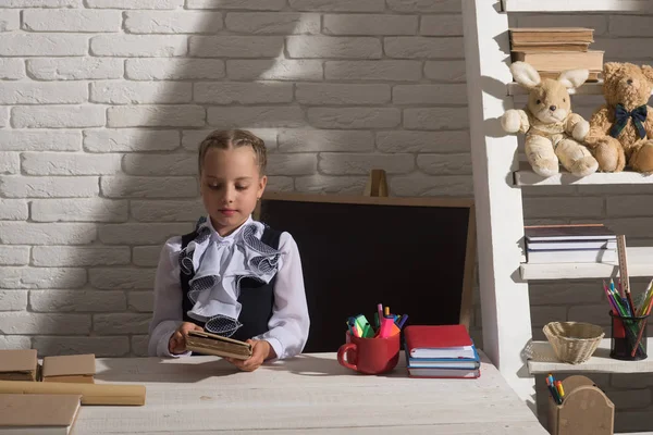 Powrót do koncepcji szkoły i edukacji. Dziewczyna siedzi przy biurku — Zdjęcie stockowe