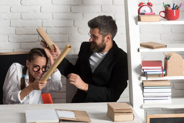 Menina com óculos e homem barbudo luta com pergaminhos — Fotografia de Stock