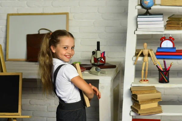 Flicka med glada ansikte uttryck nära skrivbord med skolan levererar — Stockfoto