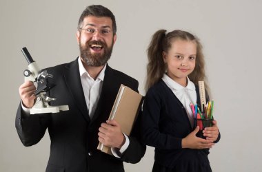 Çocuk ve baba kitap, kalem ve mikroskop tutun.