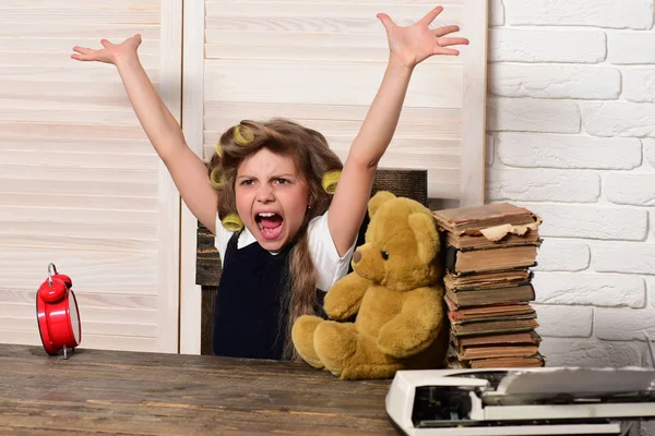 Menina pequena com urso e livro, despertador na mesa — Fotografia de Stock