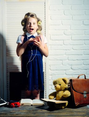 Kıvırıcı saç kulaklık ve telefon ile küçük kız.