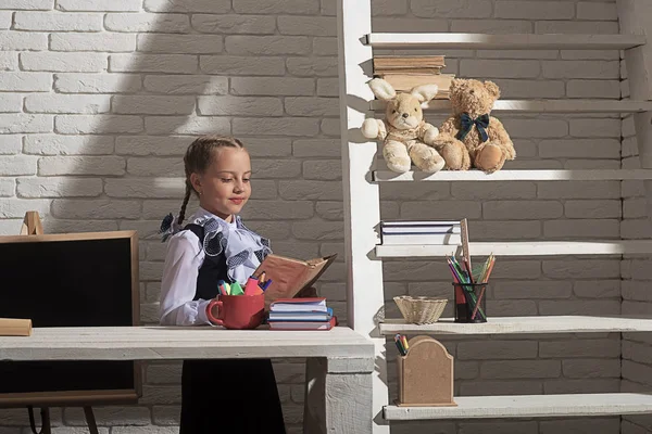 Дівчина сидить за столом з різнокольоровими канцелярськими приладдям і книгами — стокове фото