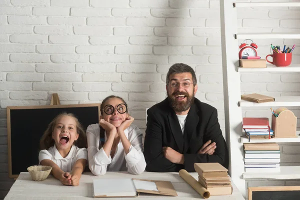 Kızlar ve sakallı adam kitaplarla masa başında oturmak