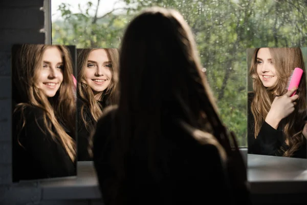 Mädchen Blick auf Spiegel mit Kamm. — Stockfoto