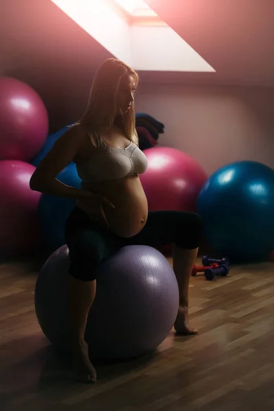 Femme enceinte assis sur la balle en forme dans la salle de gym — Photo