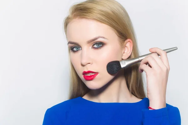 Chica con labios rojos aplicando maquillaje en la cara con cepillo — Foto de Stock