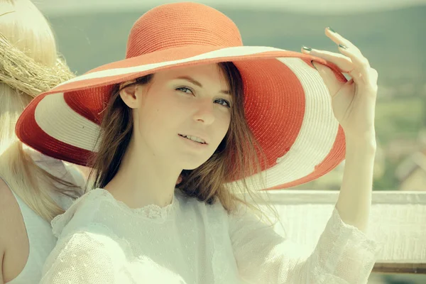 Женщина в красной шляпе позирует в солнечный день на естественном ландшафте — стоковое фото