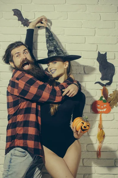 Halloween hipster gritando y abrazando mujer sonriendo en sombrero de bruja — Foto de Stock