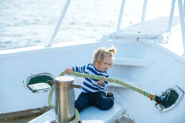 Małe dziecko siedzi i cumowania liny na biała łódź — Zdjęcie stockowe