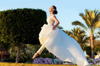 Kız tropikal peyzaj üzerinde yeşil çimenlerin üzerinde atlama