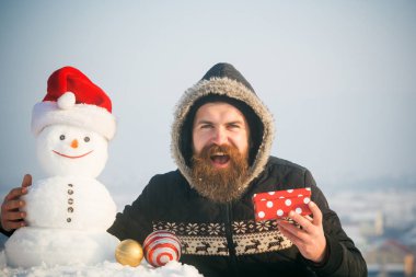 Mutlu bir adam ve kardan adam Noel Baba şapkası gri gökyüzü üzerinde