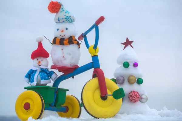 Sneeuwpoppen driewieler rijden op besneeuwde achtergrond — Stockfoto