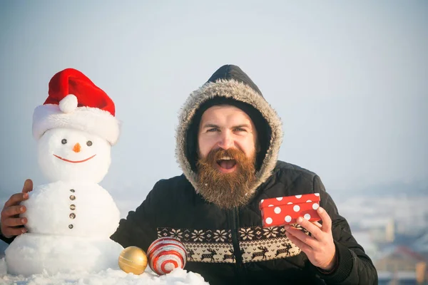 Uomo felice e pupazzo di neve in cappello di Babbo Natale sul cielo grigio — Foto Stock