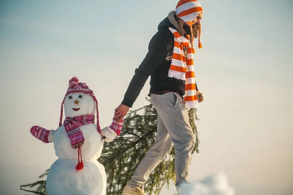 Chico y escultura de nieve con sombreros y bufandas — Foto de Stock