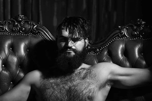 Bearded naked man on couch